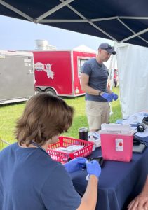 Students and faculty sit at a tent at an exhibition, providing health care screenings