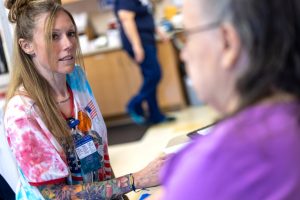 A certified medical assistant at Penn State Medical Group – gathers patient information during an appointment. She is wearing a tie-dye shirt.