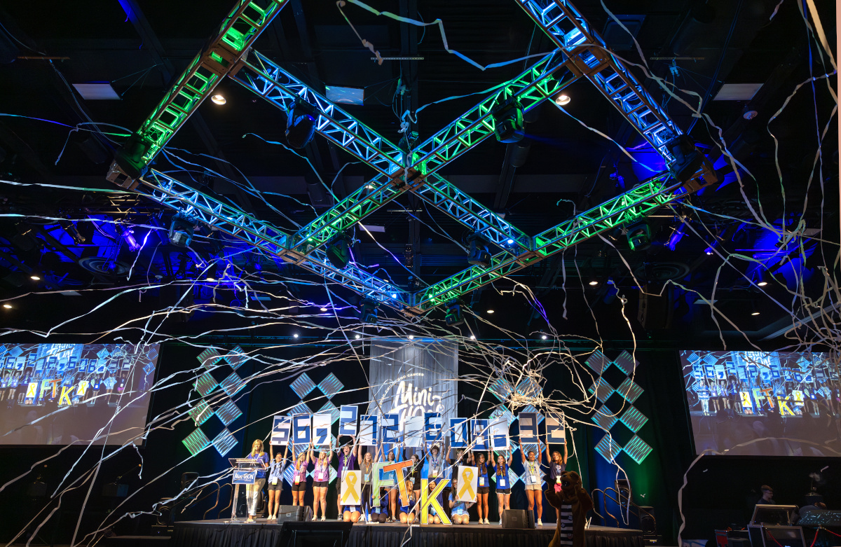 Several students hold up numbers that spell out $6,272,608.32 while streamers fly through the air in the foreground.