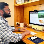 A man sits at a desk, working on a computer