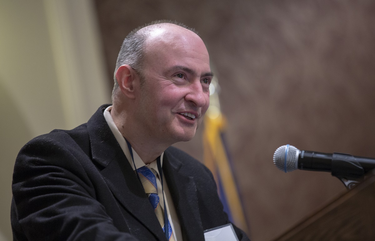 A man dressed in a suit speaks at a podium