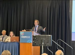 Dr. Jonathan Stine stands at a podium during his conference presenation