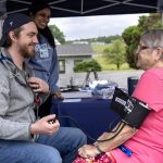 A medical student gives a woman a blood pressure reading.