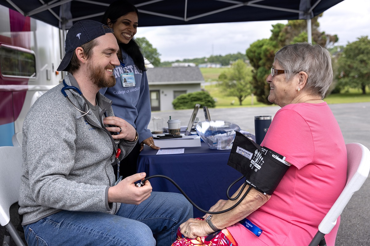 A medical student gives a woman a blood pressure reading.