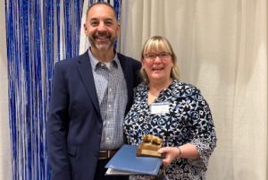 Suzanne Firestone holding an award with another person standing with her