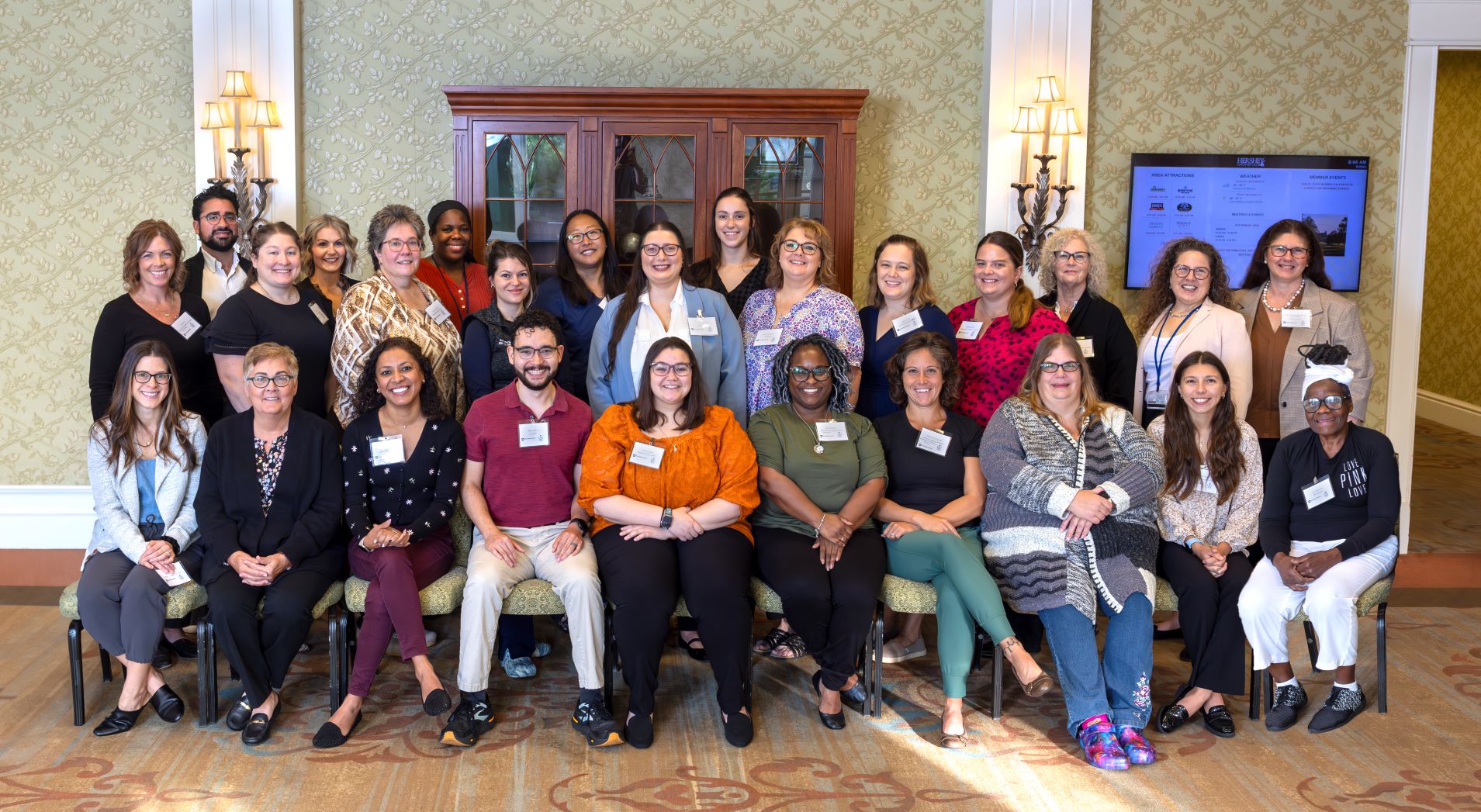 A group of people who participated in the inaugural Geriatric Scholars Program stand and sit for a photo at the Hershey Country Club in September 2024