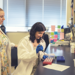 Two women wearing white coats work in a research lab