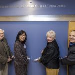 Four people cut a ribbon to present a plaque to name a research laboratory