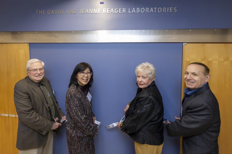 Four people cut a ribbon to present a plaque to name a research laboratory