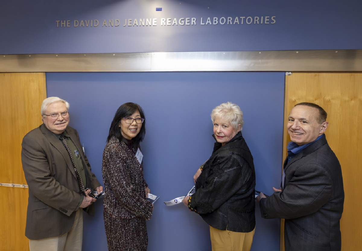 Four people cut a ribbon to present a plaque to name a research laboratory