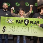 Three people smile enthusiastically as they pose with poster containing the dollar amount $387,731.16.