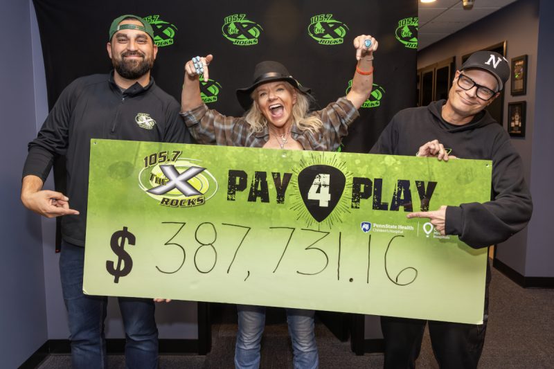 Three people smile enthusiastically as they pose with poster containing the dollar amount $387,731.16.