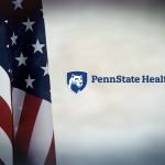 An American flag hangs down on the left, and to the right is the Penn State Health logo.