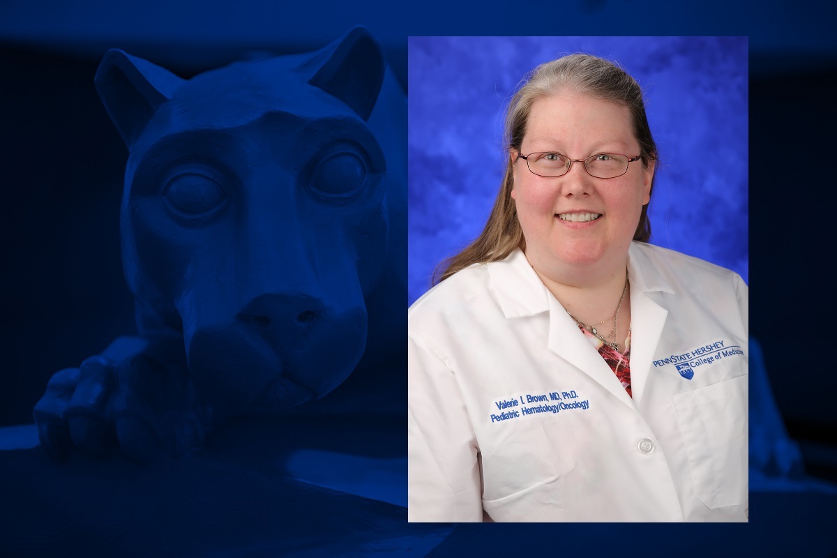 A photo of a women smiling for a headshot. She is wearing a white doctor's coat.