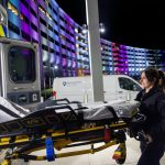 A life Lion paramedic smiles while loading a stretcher into an ambulance outside Penn State Health Milton S. Hershey Medical Center at night.