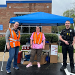 Two colleagues and a police officer stand with collection boxes and sharps containers outside a medical practice.