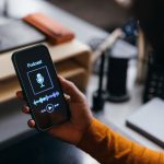 A close up view of a hand holding a cell phone showing a podcast.