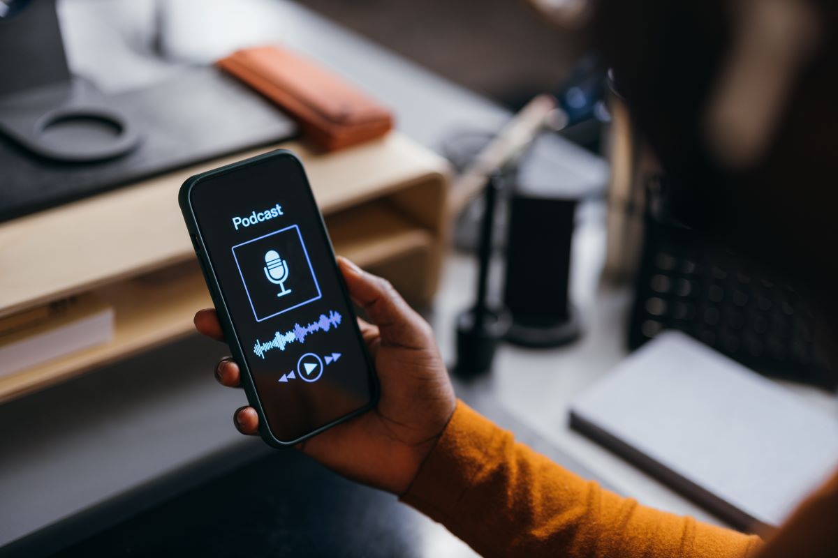 A close up view of a hand holding a cell phone showing a podcast.