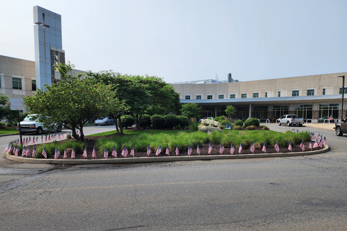 Small American flags stuck in the ground around a garden in front of a St. Joseph Medical Center