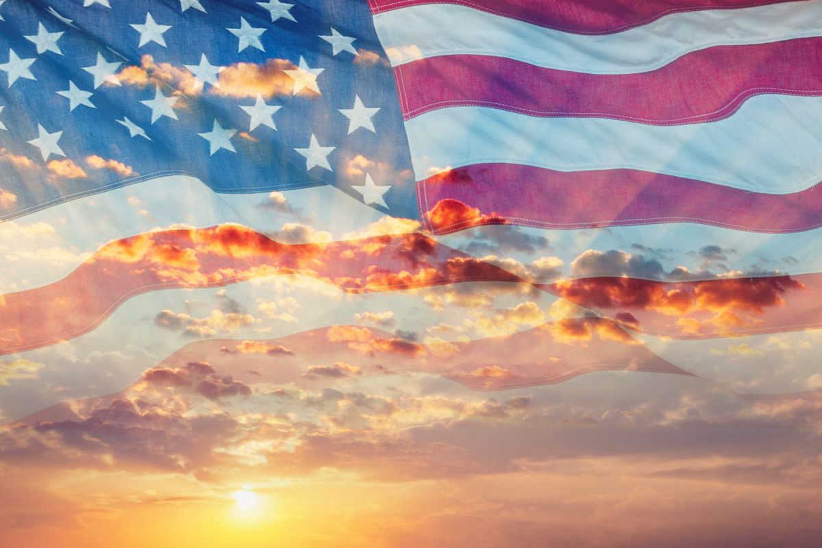 An American flag overlaid on a sunrise sky.