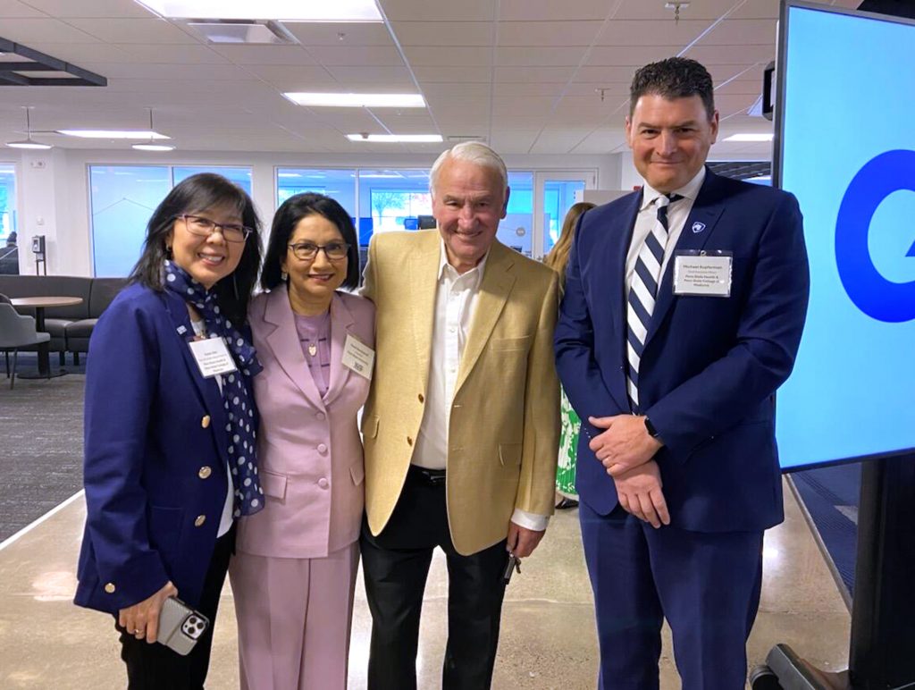 Four people in professional attire smile as they pose for a photograph.