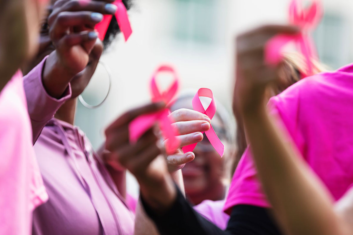 People standing together holding breast cancer ribbons.