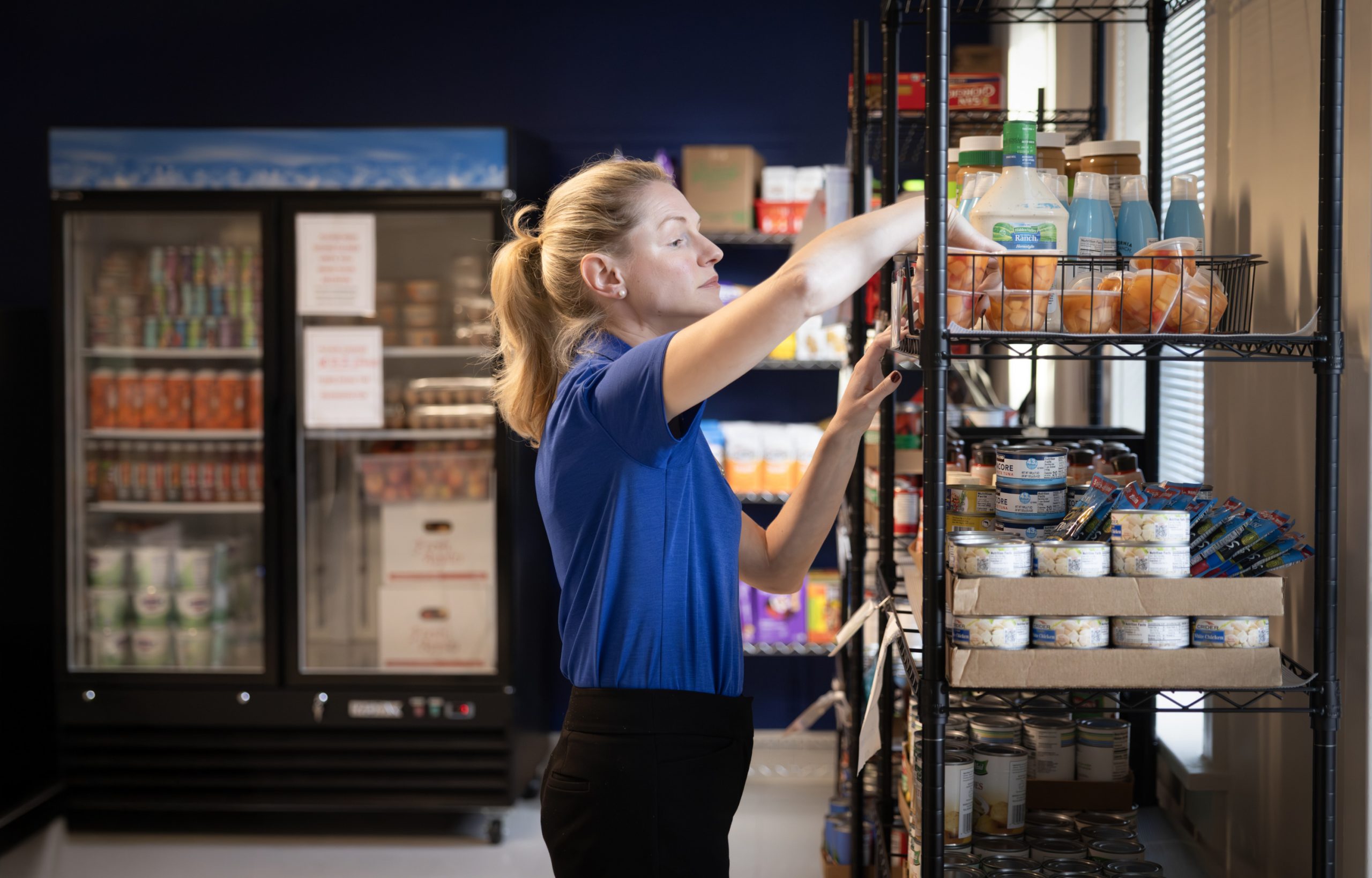 A person stacks grocery items on shelves.