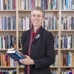 Humanities Chair poses in front of bookcase.