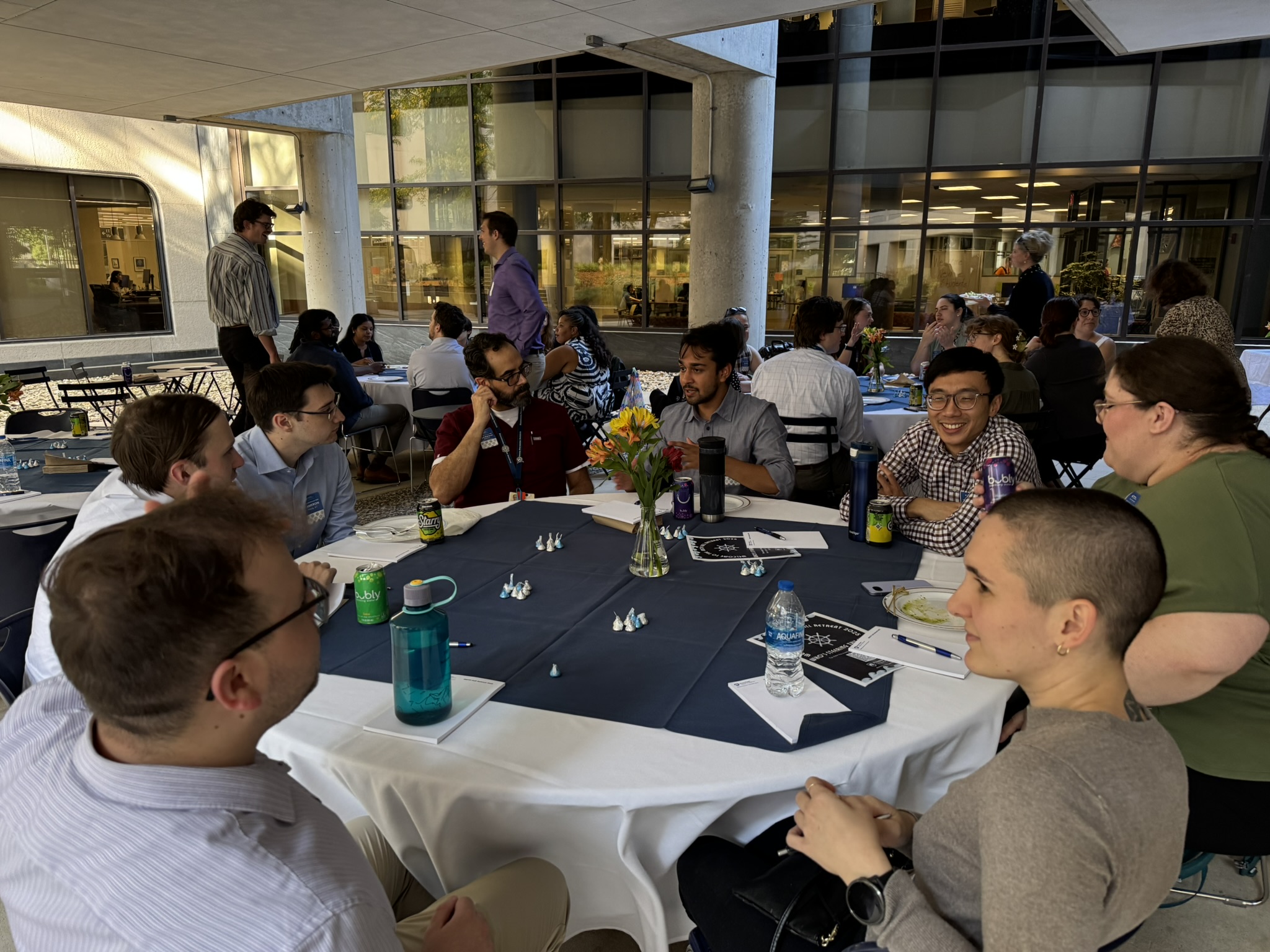 A group of people sits at a table under a patio pavilion.