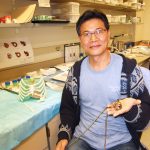 Scientist sitting in a lab and holding a prototype of a heart pump