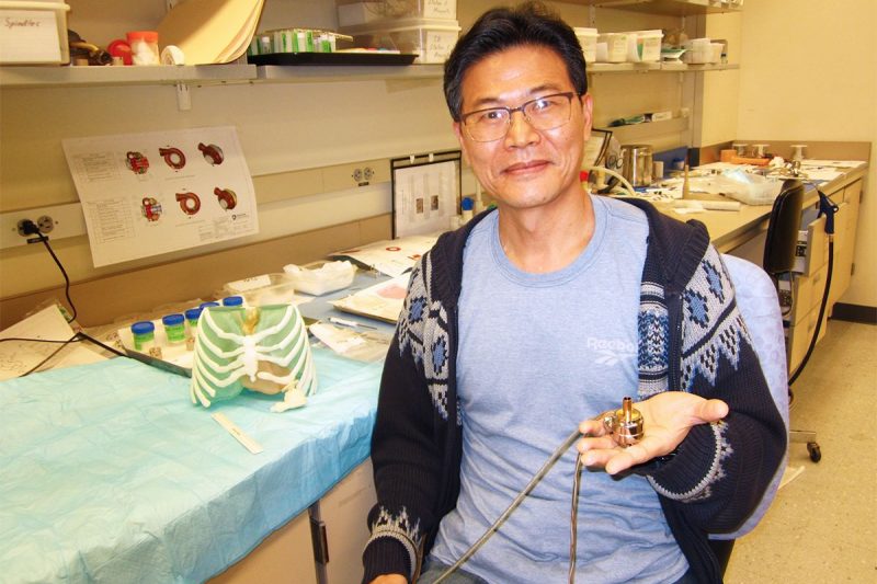 Scientist sitting in a lab and holding a prototype of a heart pump