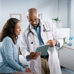 Doctor holding a tablet and speaking to a patient