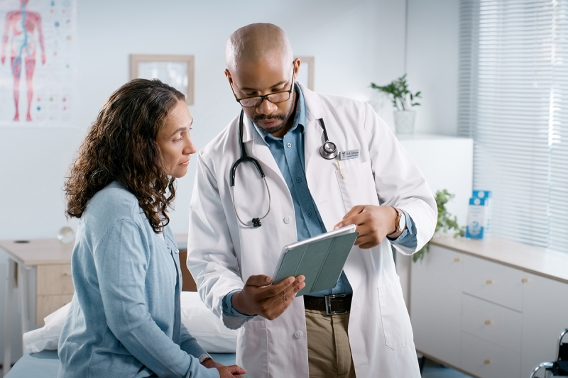 Doctor holding a tablet and speaking to a patient