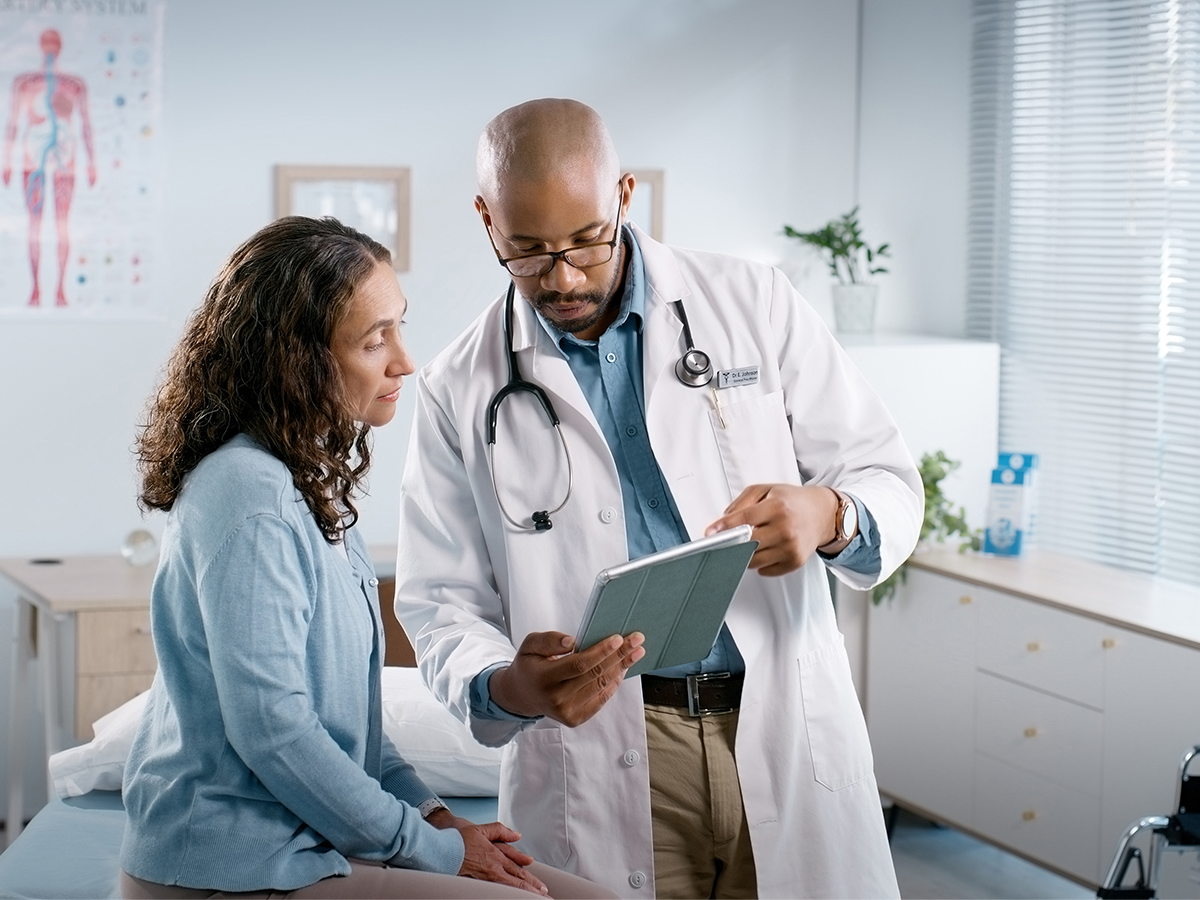 Doctor holding a tablet and speaking to a patient