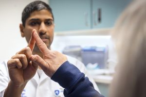 A doctor wearing a white coat touches his index finger to a patient’s index finger to test her coordination. 