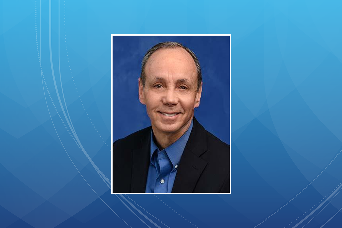 A bust photo of a gentleman in a business suit, smiling.