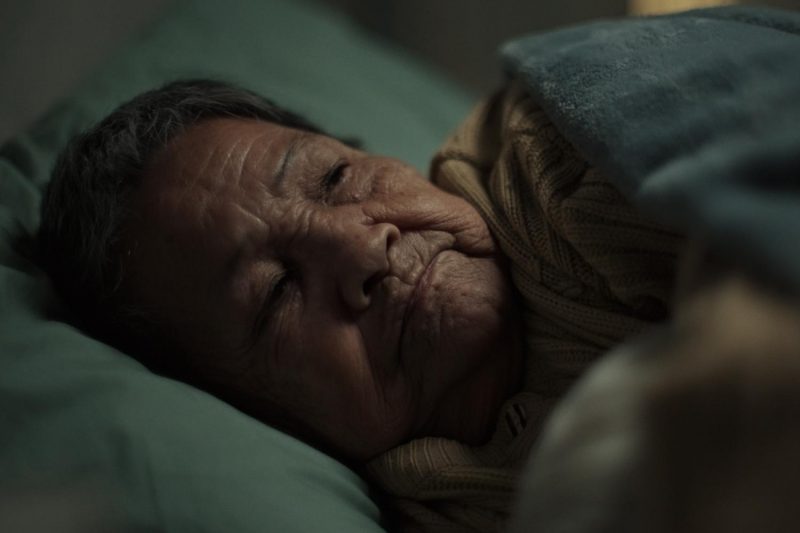 Close-up of an elderly woman lying awake in a dark room