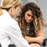 Young person seated facing a therapist in a white coat