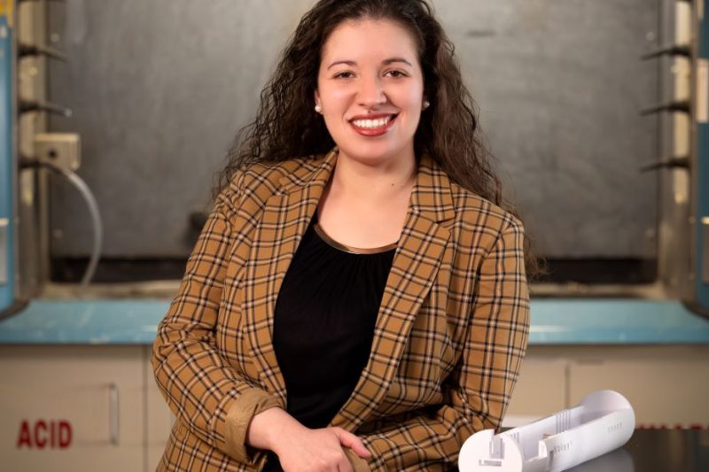 A professional portrait of Corinne Augusto, with a research lab in the background.