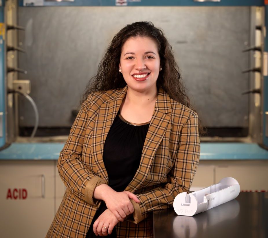 A professional portrait of Corinne Augusto, with a research lab in the background.