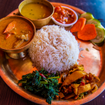 Rustic food plate with rice in the middle and other ethnic foods around it