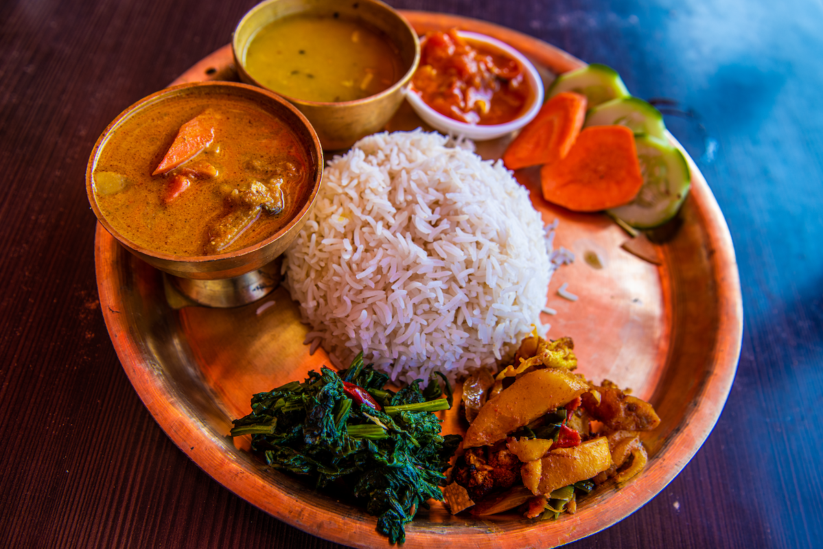 Rustic food plate with rice in the middle and other ethnic foods around it
