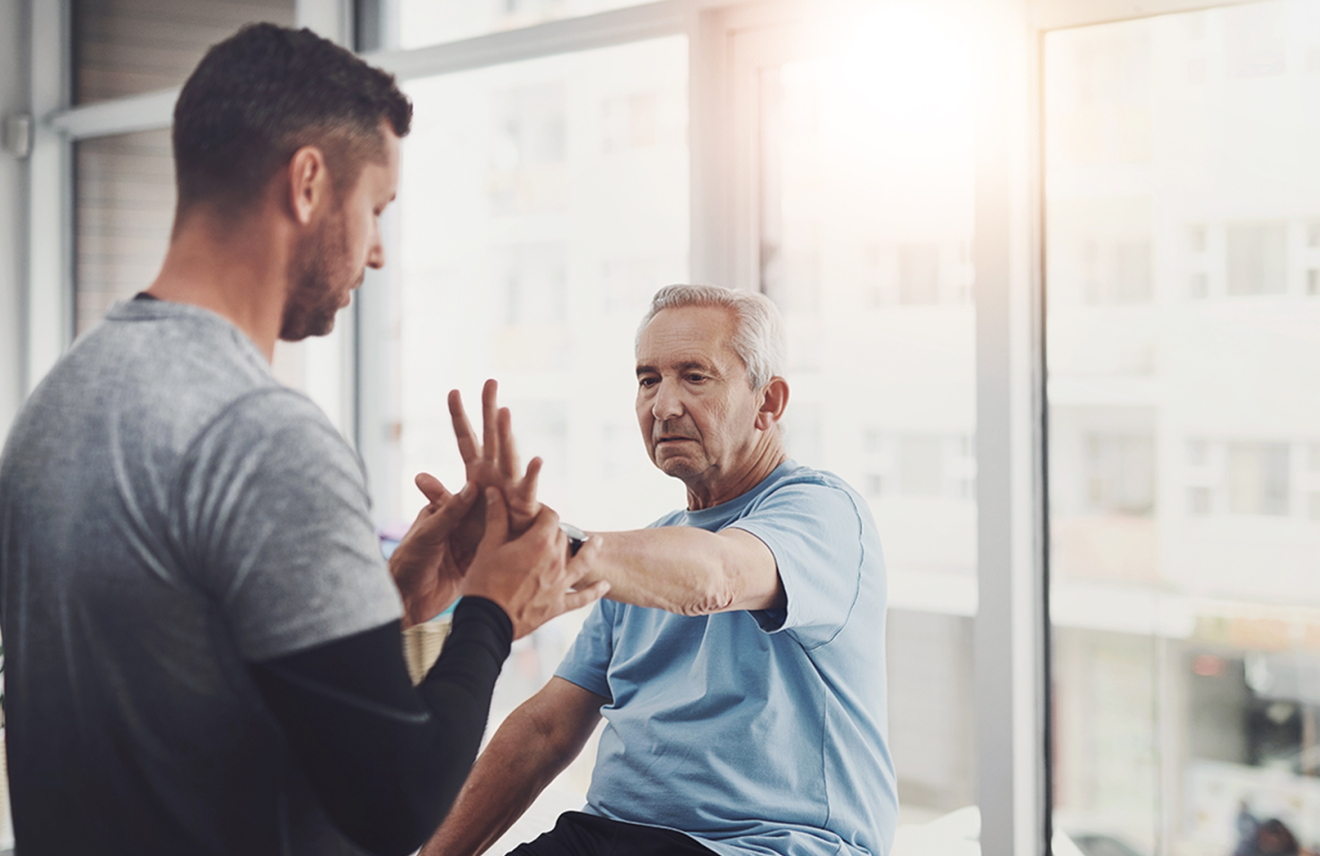 Older man doing hand therapy exercises with a physical therapist
