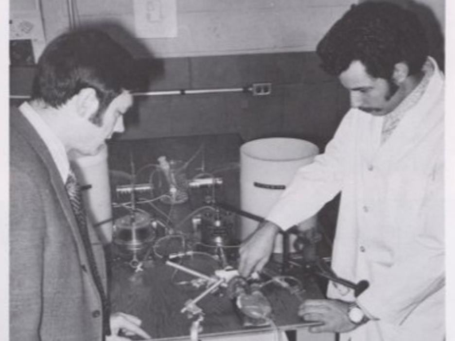 A black and white picture of two researchers working on an artificial half heart