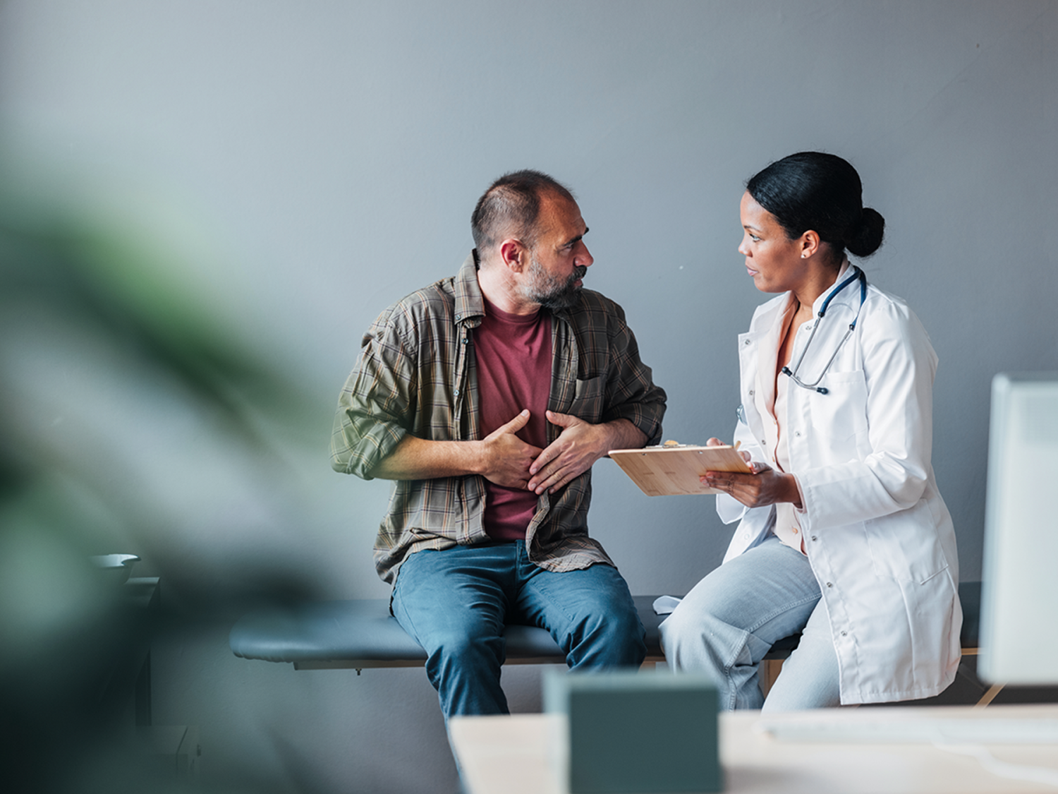 A person gesturing to their stomach and speaking with a doctor