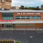 Part of a hospital building with an "Emergency" sign on it and a sign that says, "John R. Dietz Emergency Center."