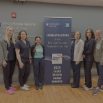 Six people pose around a sign that says, "Congratulations to our Heart and Vascular Progressive Care Unit 2025 Silver Beacon Award Winners."