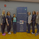 Six people pose around a sign that says, "Congratulations to our Heart and Vascular Progressive Care Unit 2025 Silver Beacon Award Winners."