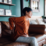 Person sitting on couch with hand on their back