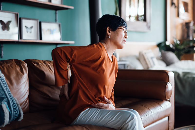 Person sitting on couch with hand on their back